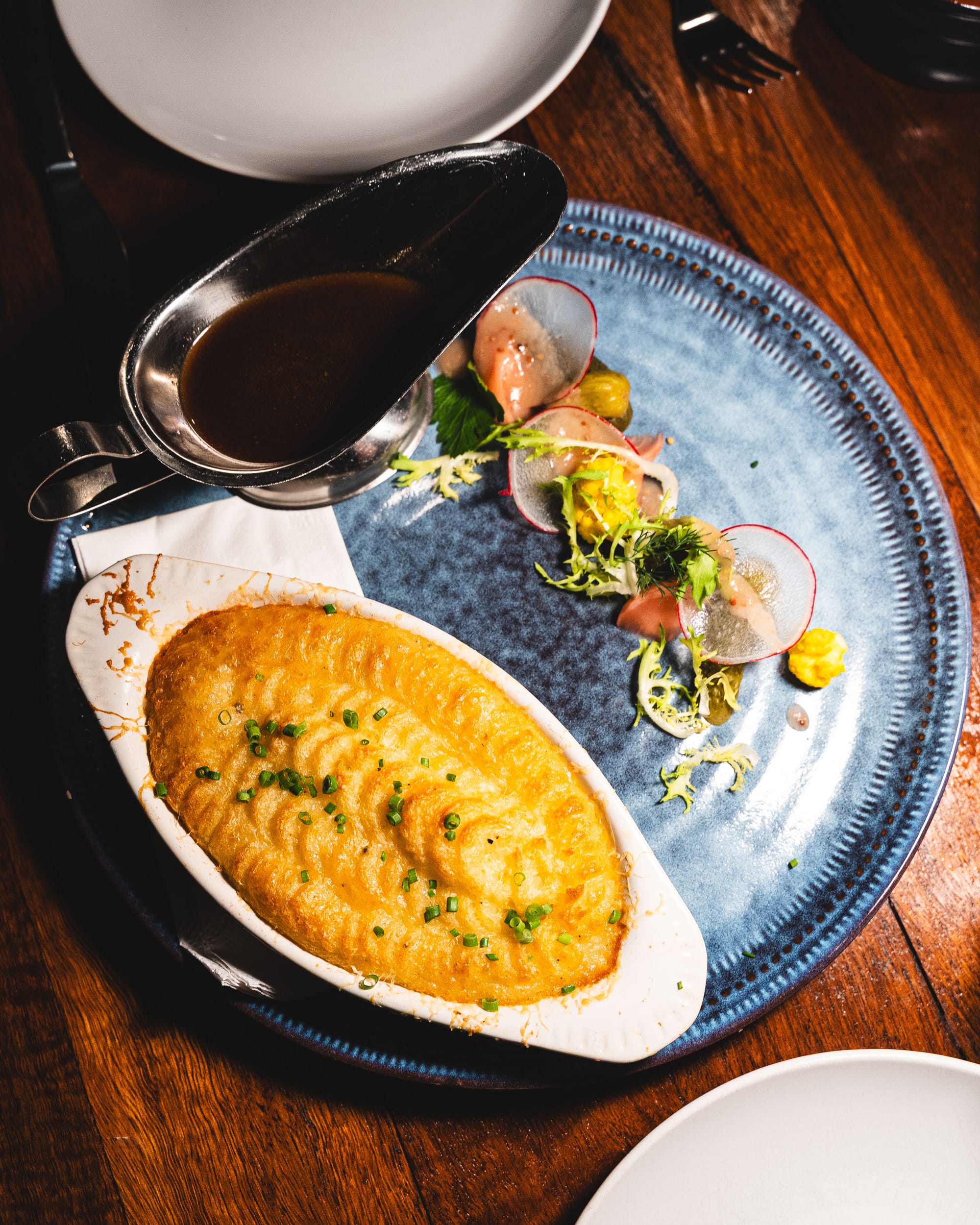 Duck pie with gravy in sauce boat and side salad