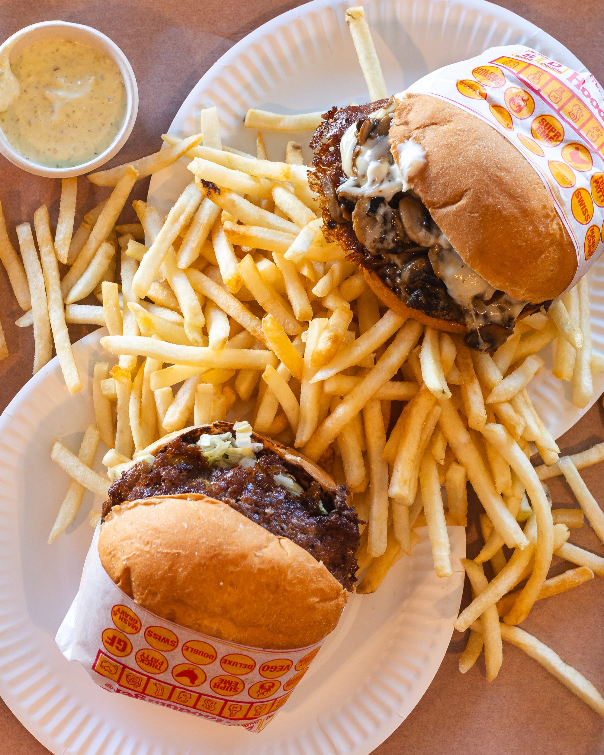 Top down shot of burgers on paper plates with fries