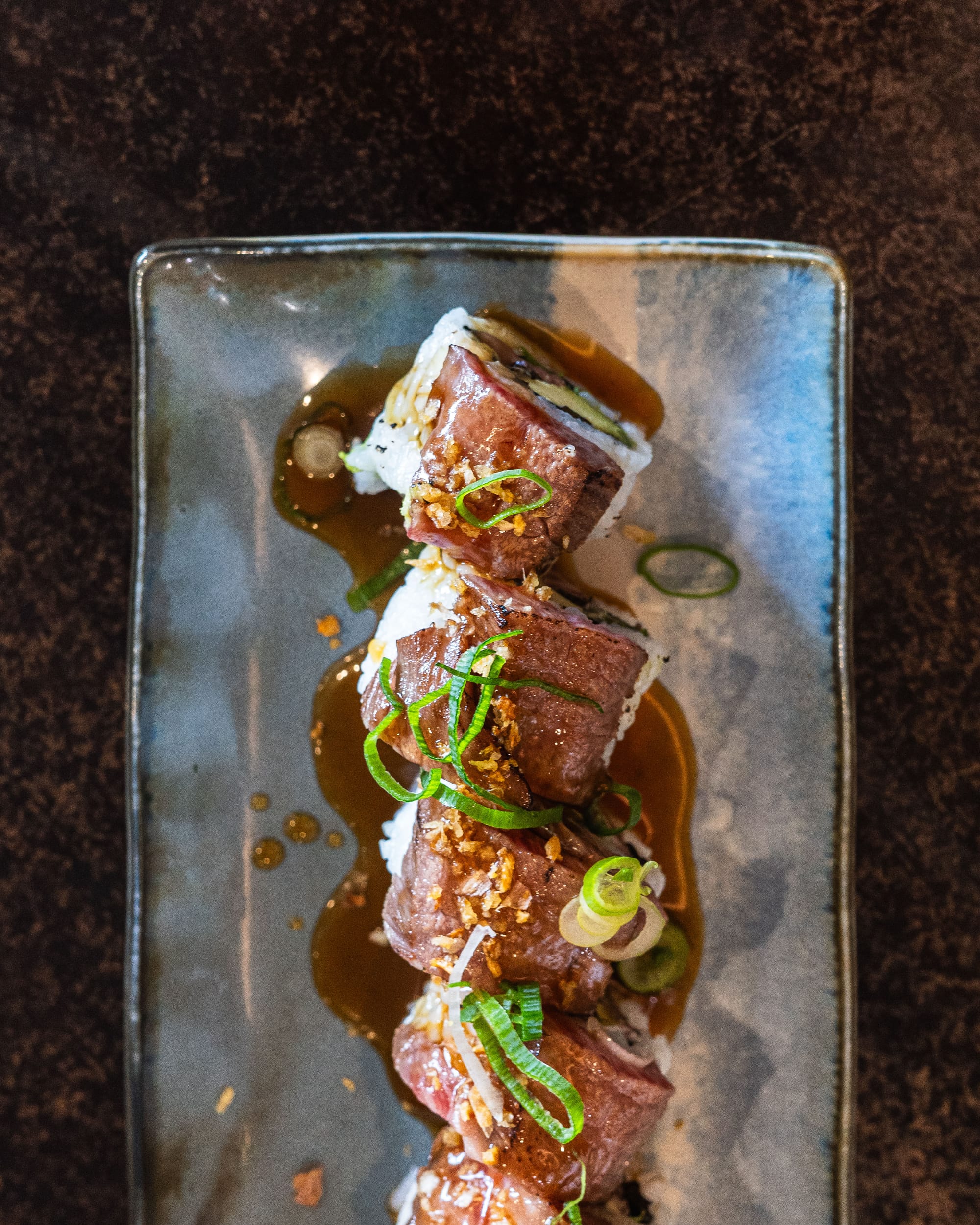 Top down shot of sushi roll with wagyu placed on top 