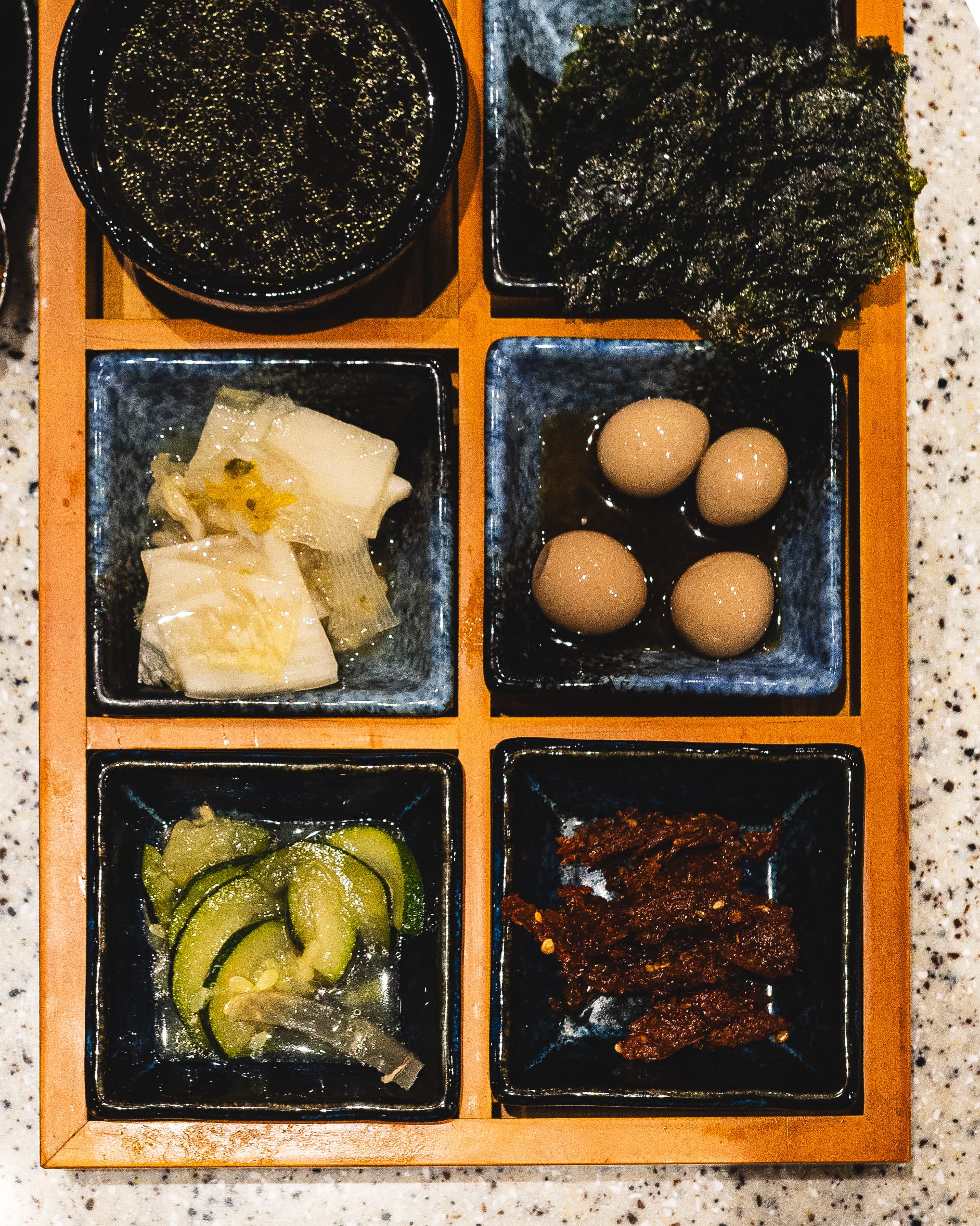 Close up of side dishes - seaweed soup, seaweed, kimchi, quail eggs, cucumber and anchovy