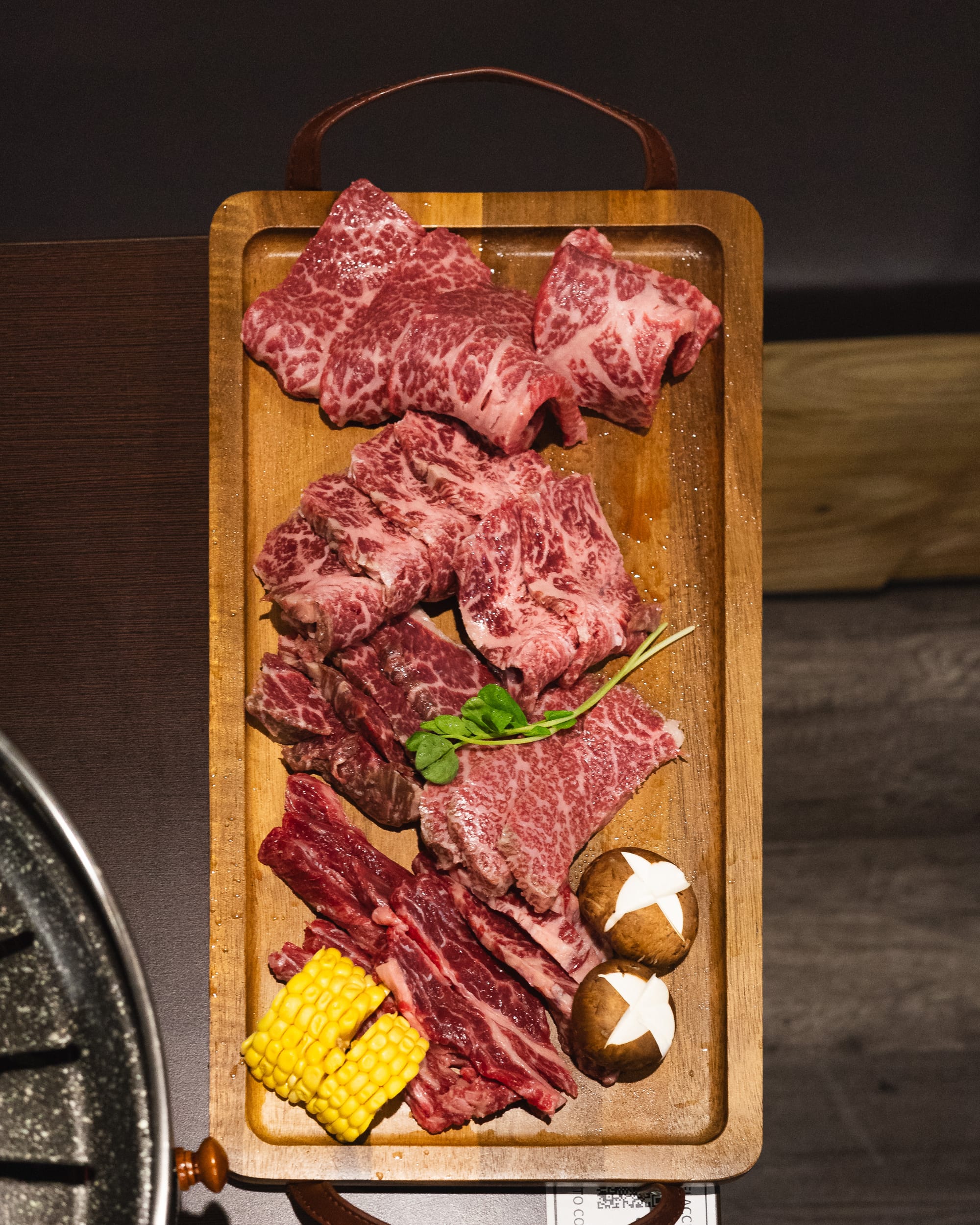 Top down shot of a board with raw wagyu with decorative mushrooms and corn