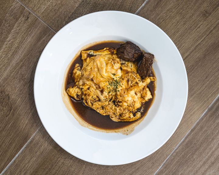 Close up of omurice with demi-glace sauce and two chunks of stewed beef