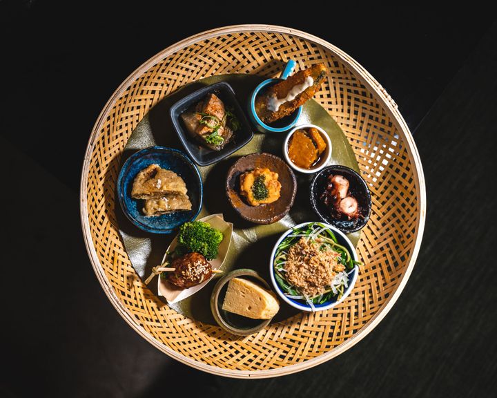 A circular basket with 9 different Japanese dishes 