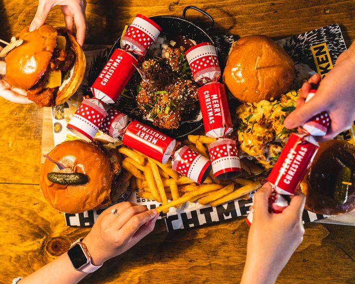 Overhead shot of people reaching into a platter for burgers and chips
