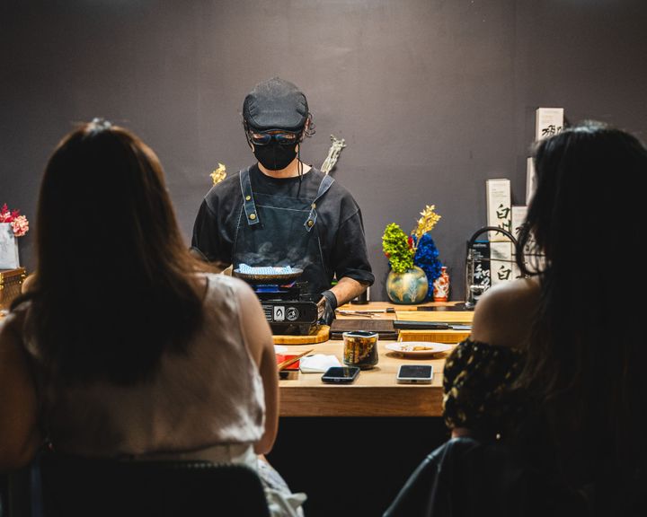 Chef standing behind counter cooking off a portable gas stove