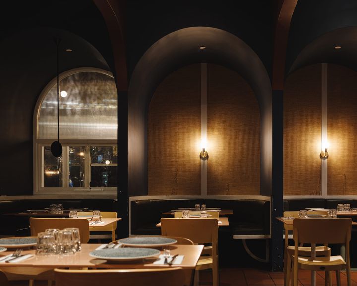 Interior of restaurant showing arches by booth seating and wooden tables