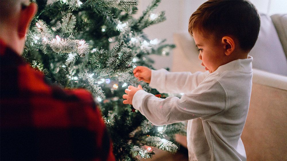 A boy decorating a tree for the holidays
