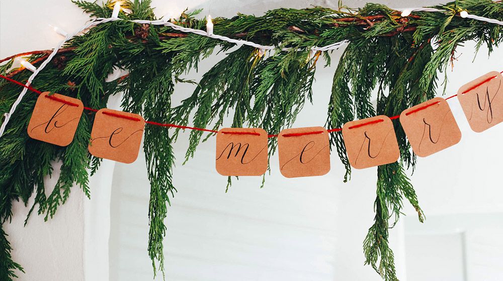 Festive holiday letters and greenery hang over a doorway