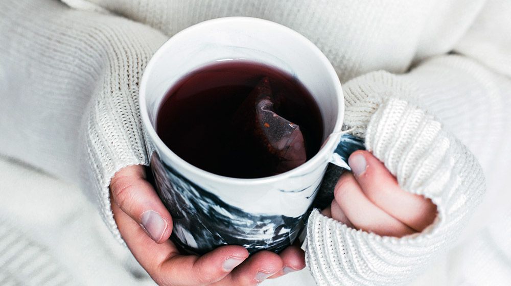 Hands holding a hot cup of tea