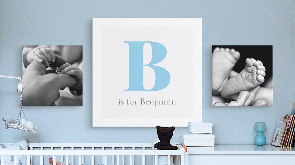 A monogram canvas print and two photo canvas prints hanging over a crib in a nursery