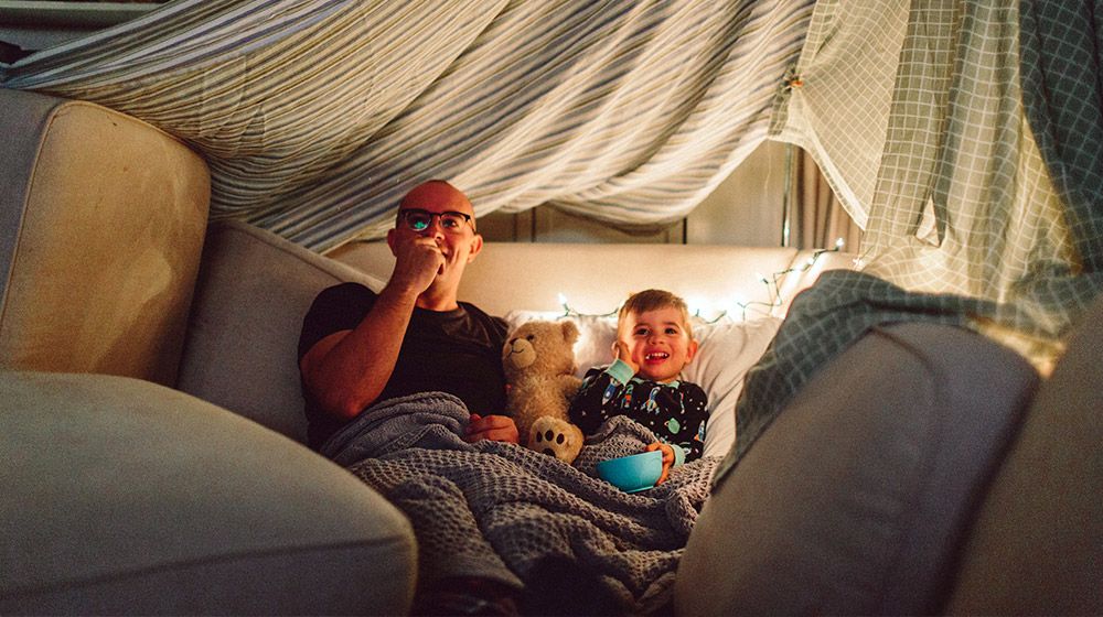 A father and son enjoy an indoor movie night