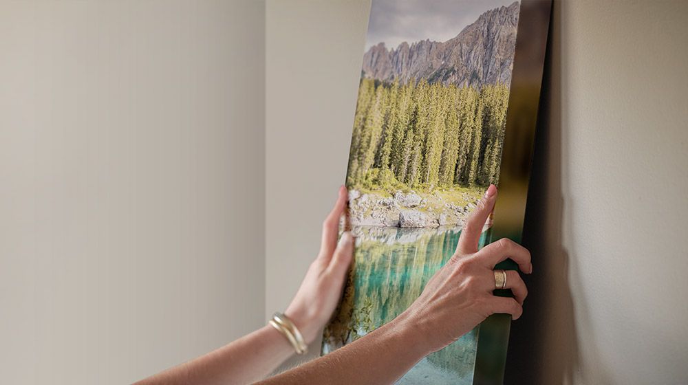 person easily hanging a canvas photo print on their wall of a forest and lake
