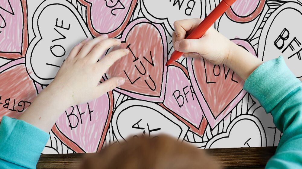 photo of boy coloring a valentine's day coloring canvas with red and pink markers