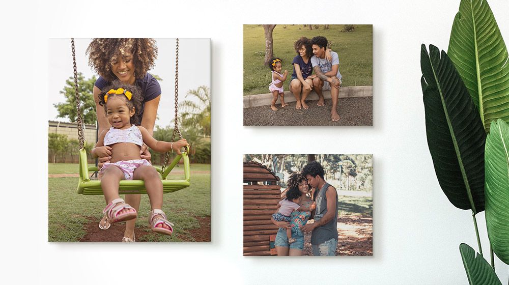 Three canvas prints of two parents and their child on a minimal white wall.
