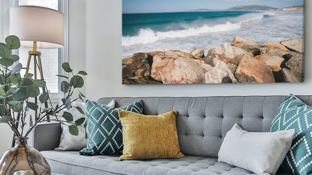 Large Canvas print of a beach over a gray couch in a contemporary living room.