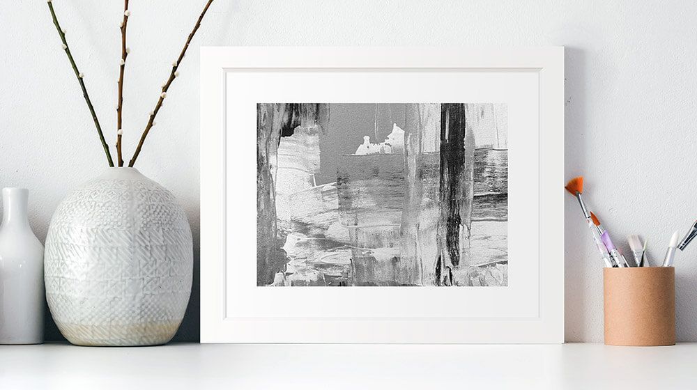 A framed print of an abstract painting sitting on a shelf