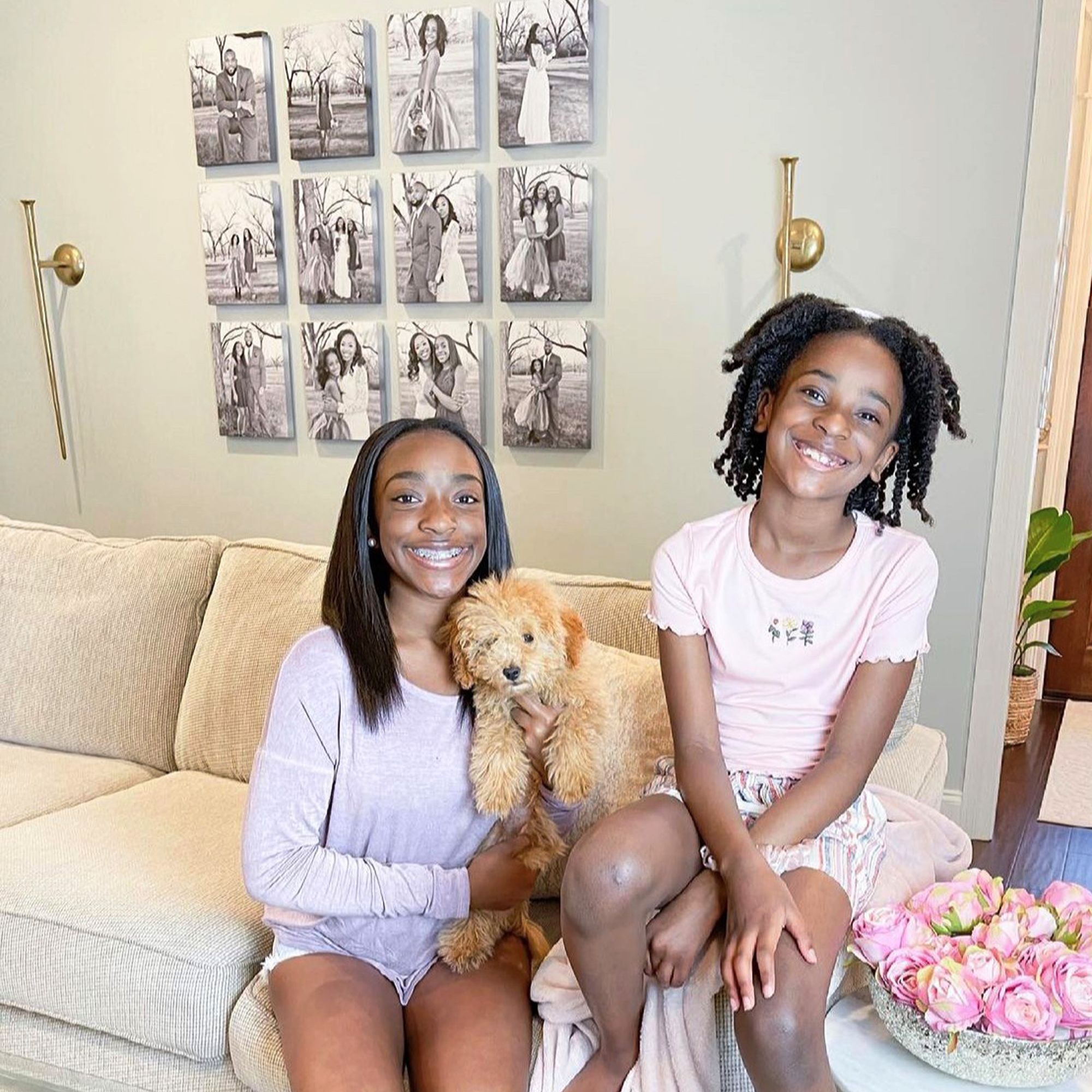 Two kids and their dog sitting in front of their photo gallery wall