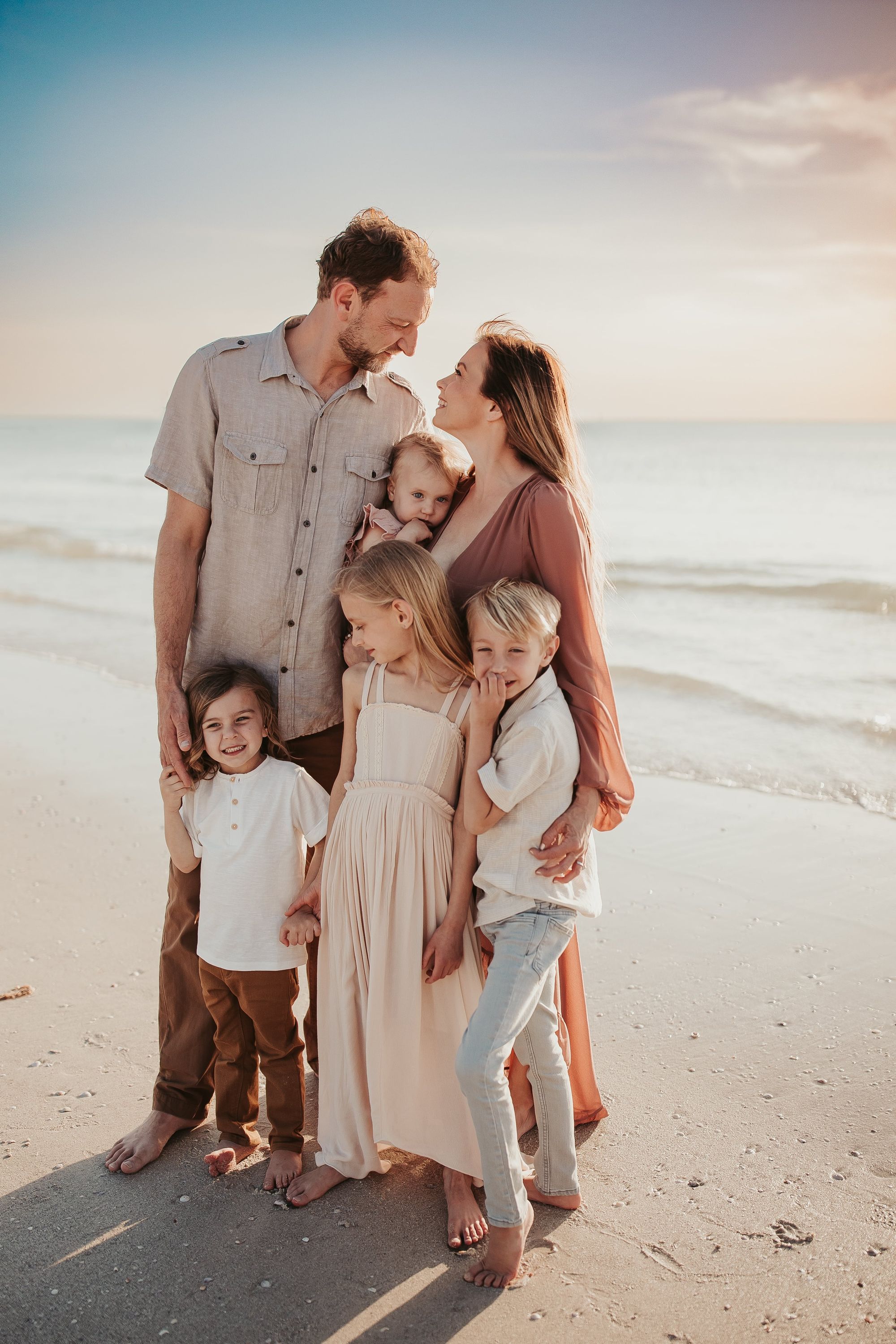 A family standing closely posed in a group photoshoot at the beach