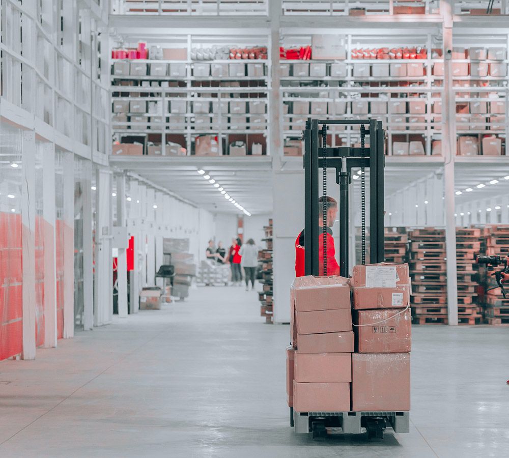 A shipping carrier carrying many packages on a trolley inside a shipping warehouse