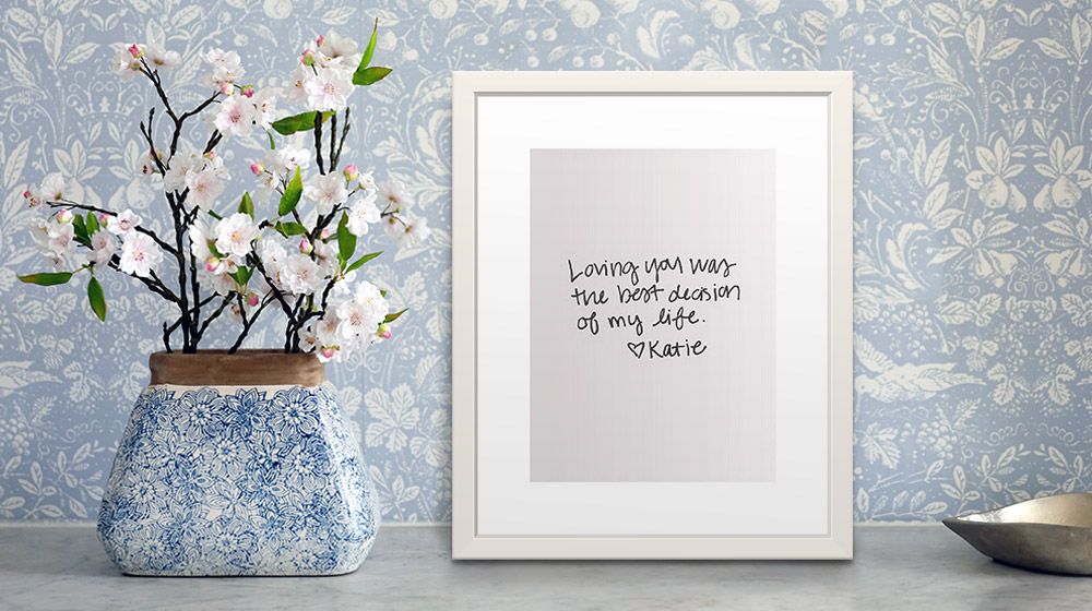 framed print of handwritten love letter, sitting on table next to vase of flowers
