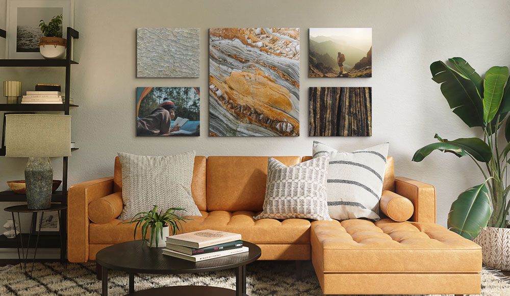 A earth toned living room has 5 canvas prints symmetrically arranged, each picture textures found in nature or are pictures of a person lost in nature scenes 