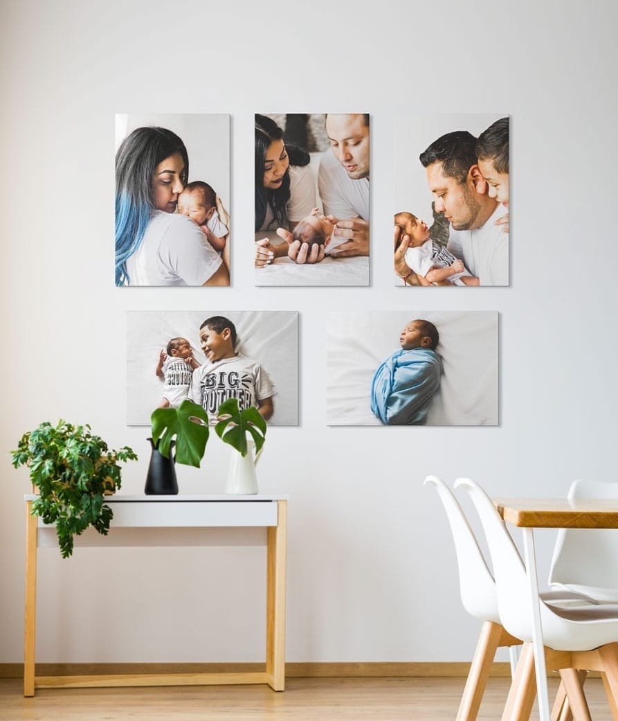 Canvas prints of a family newborn photo shoot hung on a white wall