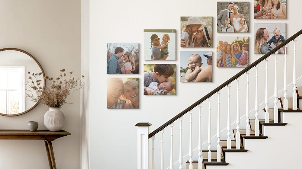 ten canvas prints hung across a wall above a staircase depicting family pictures