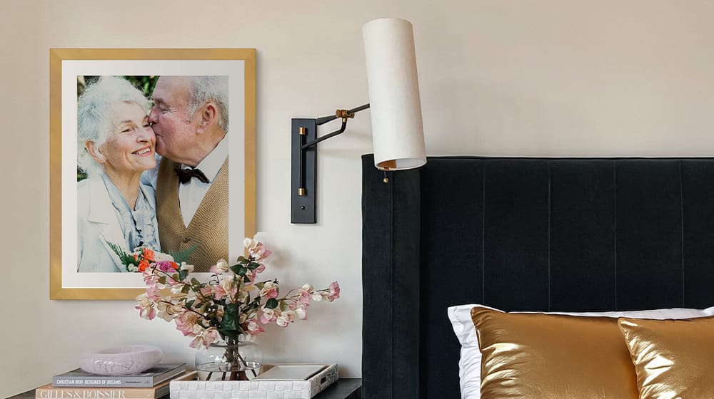 framed print of a picture from a wedding hung above an end table next to a bed