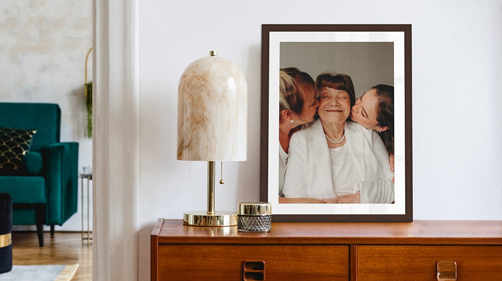 Framed canvas print of a grandmother with her daughters displayed on a dresser