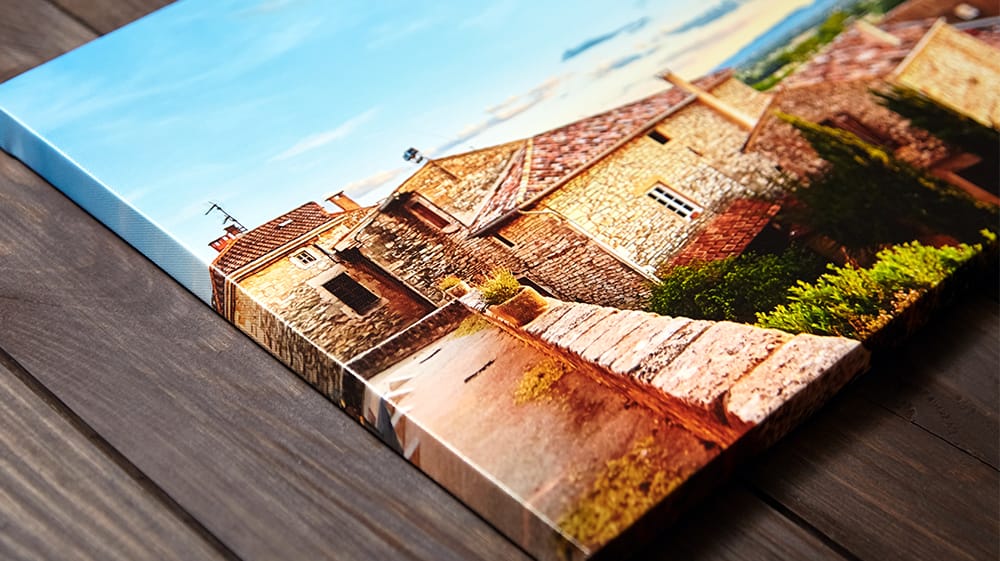 Gallery-wrapped canvas print featuring a clear, colorful photograph of a sunlit stone village.