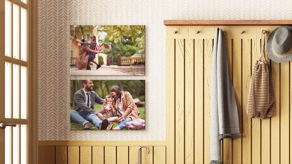 Two family photo canvases hang in an entryway, showing a parent with a child and a family enjoying time outdoors.