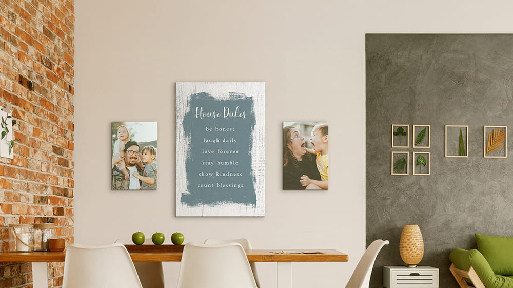Vertical family photo canvases filling narrow wall spaces around a larger typography print in a dining area.