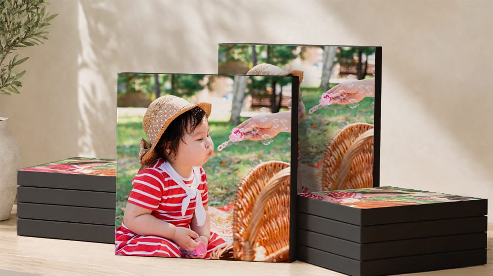 Ten square canvas prints with black edges featuring a child blowing bubbles, arranged in two stacks with two upright prints.