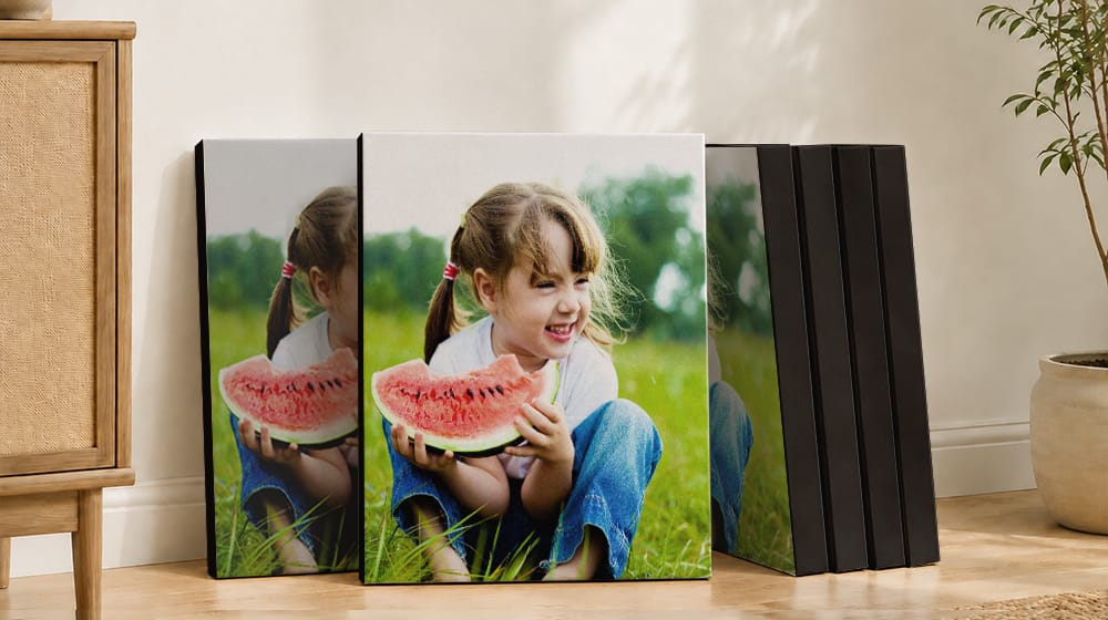 Six canvas prints with black edges showing a smiling child holding a watermelon slice, leaning against a wall.