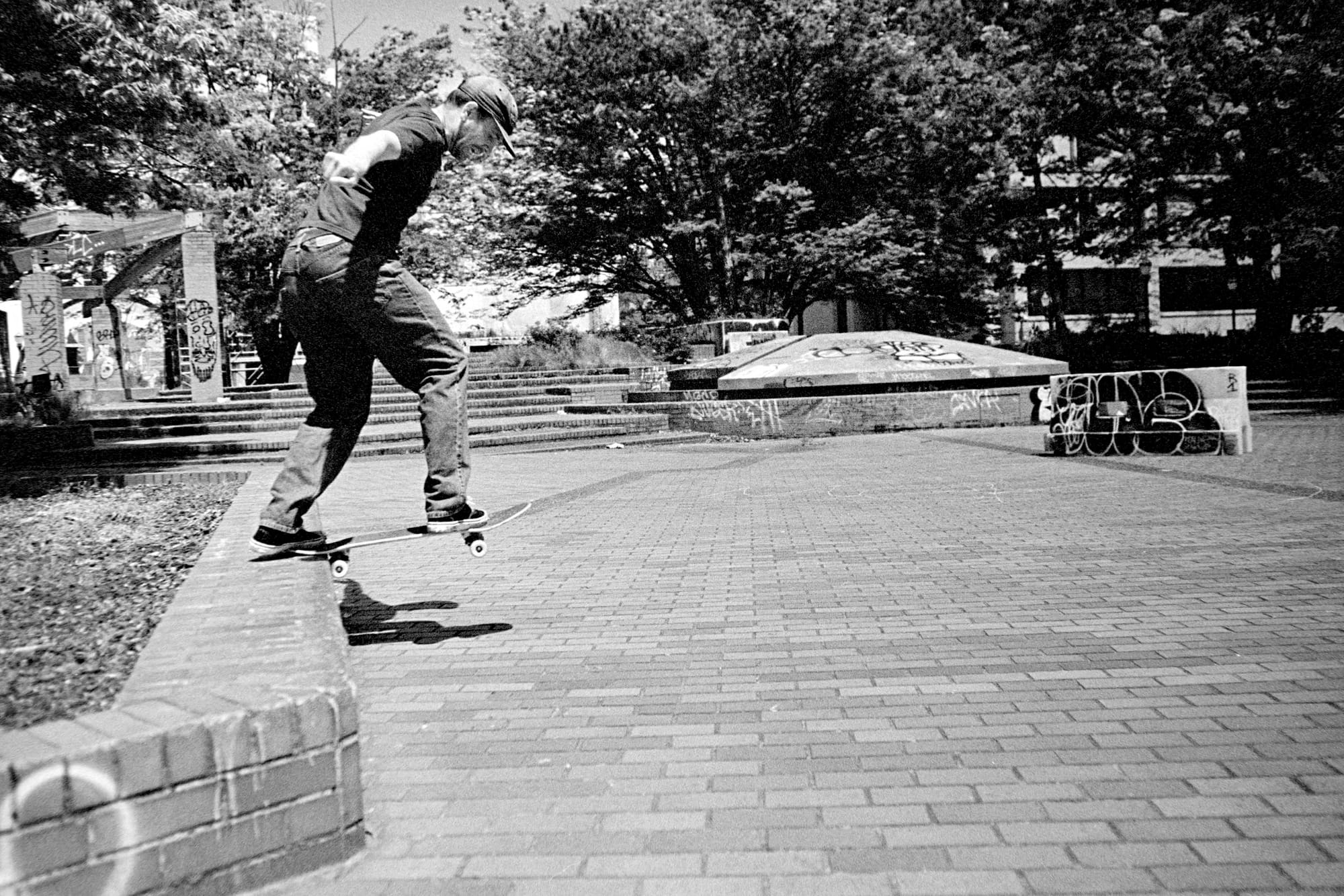 goofy footed skater doing a backside tail slide on a brick ledge.