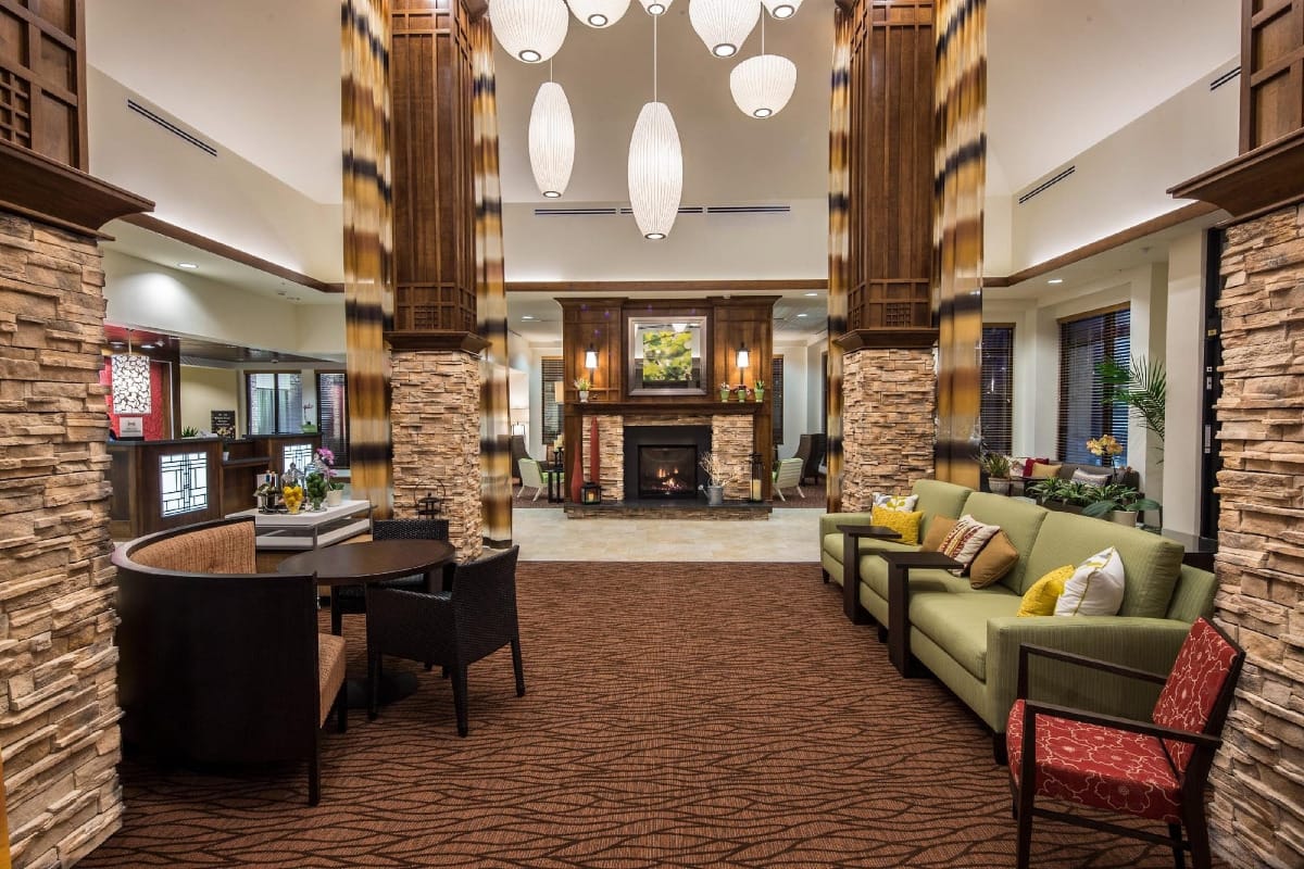 Hotel lobby with stone pillars, couches, fireplace, and ceiling lights