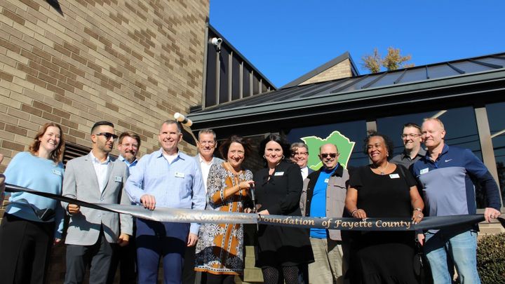 Line of Community Foundation board members and staff with ribbon in front of their new building