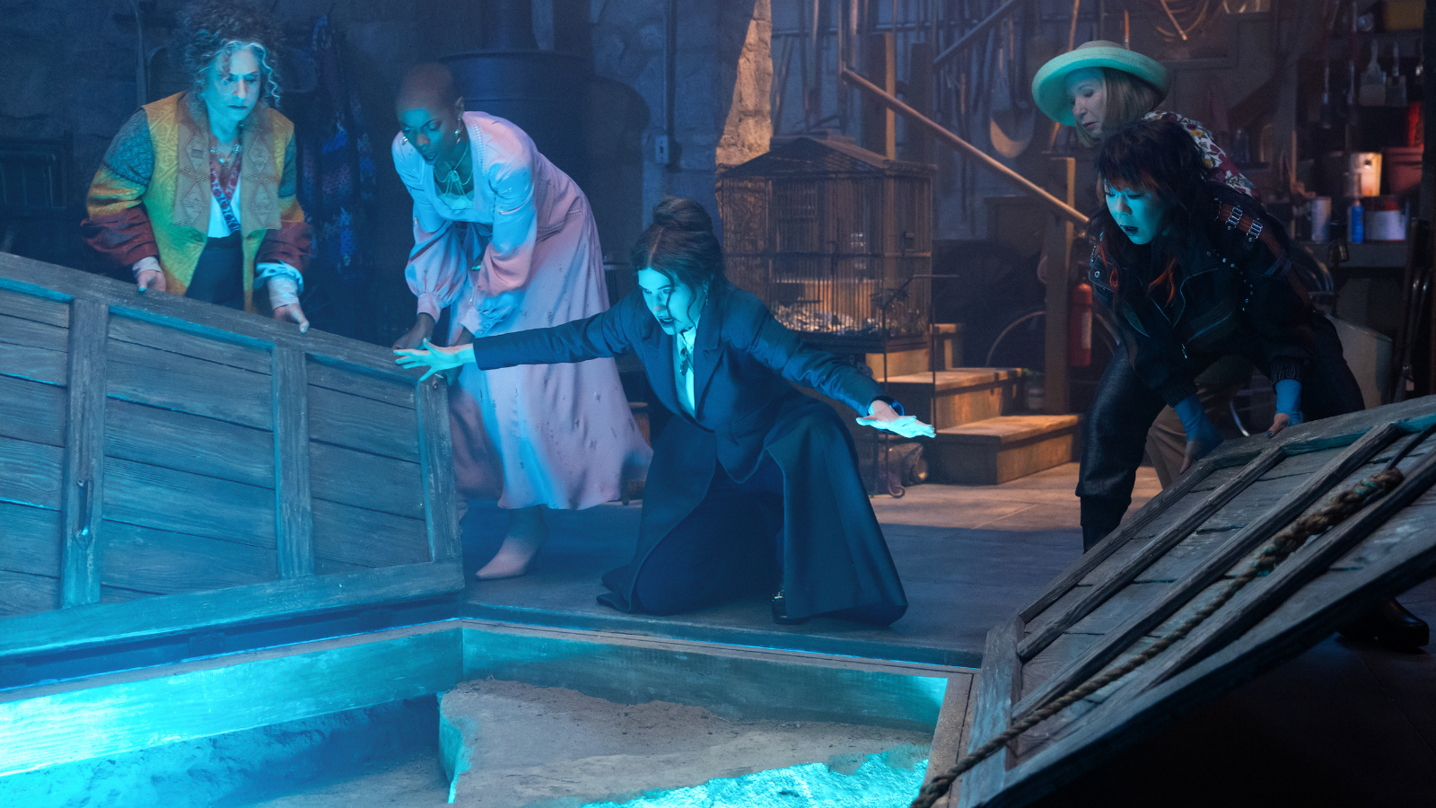 Agatha opening the door to the Witches' Road as a blue light shines out of it.