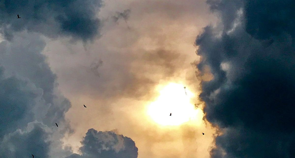 Dark clouds with sun in the middle bursting through.