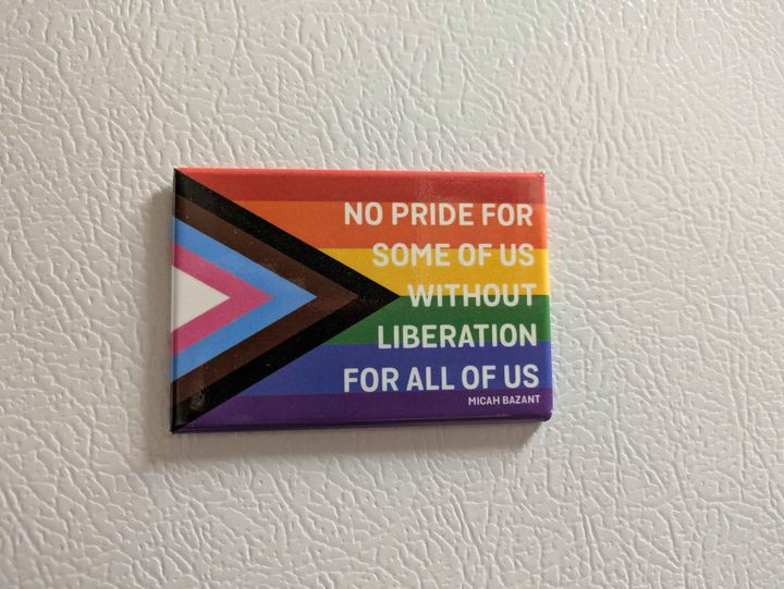 A magnet with the progress pride flag on it with the quote 'No pride for some of us without liberation for all of us.'