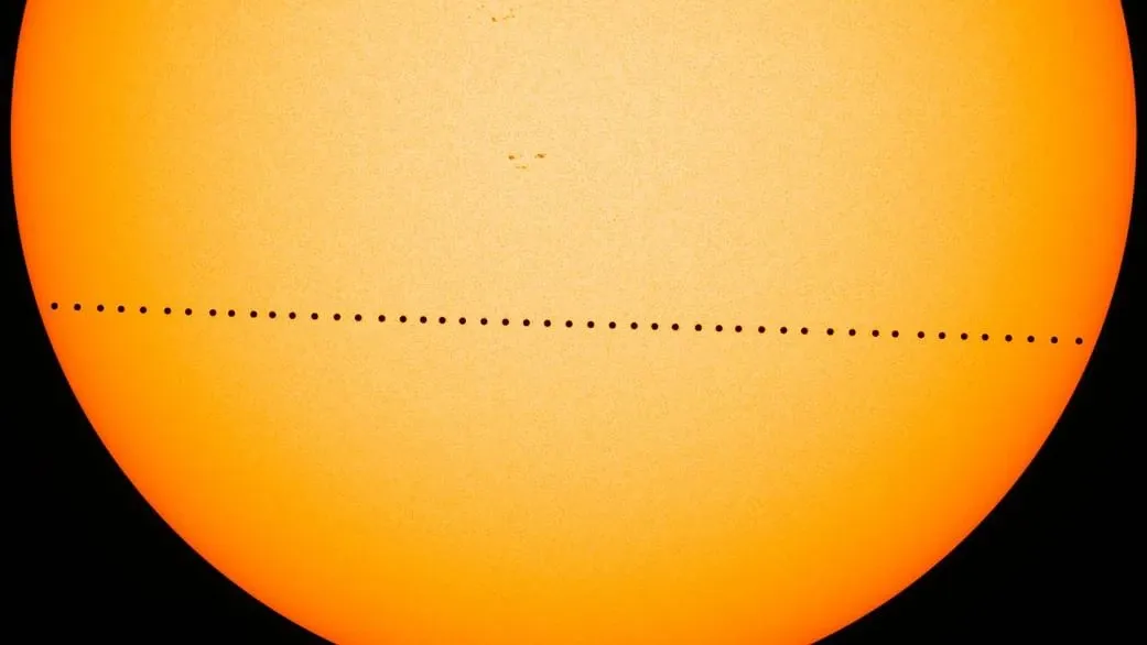 Successive dark positions of Mercury form a line across the lower part of an orange Sun.