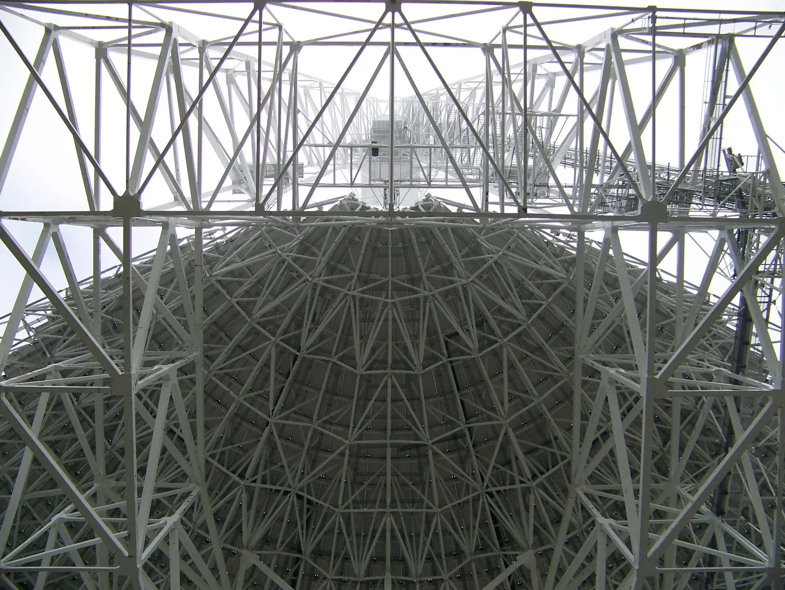 Steel trusses beneath a giant radio dish converge toward the telescope’s elevated receiver arm.