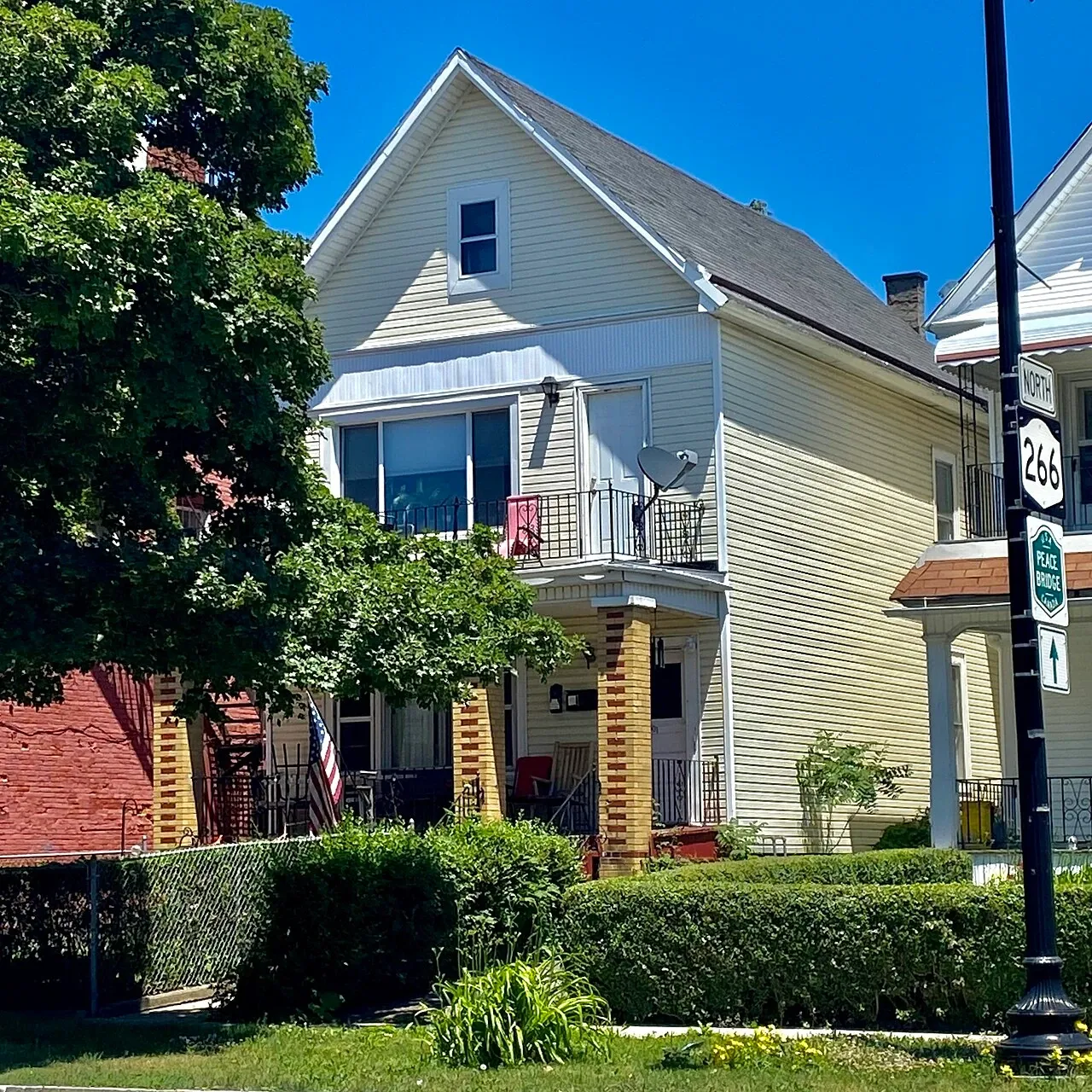 A two-storey wood-framed Buffalo house with a gabled roof and upper balcony