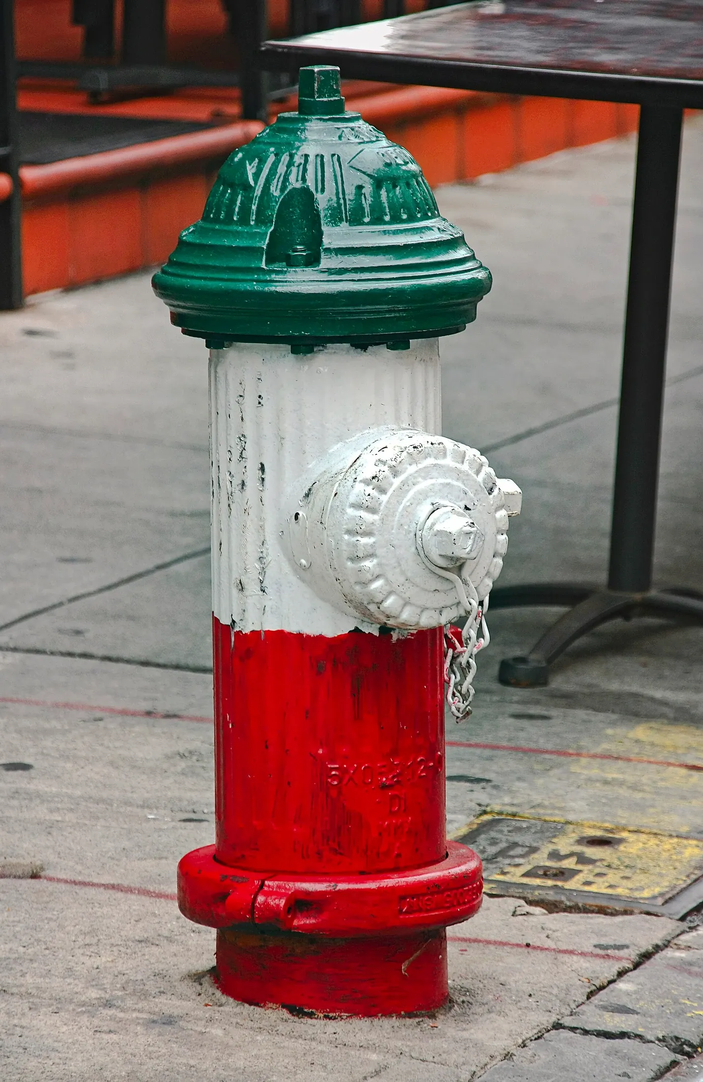 A fire hydrant painted green, white and red on a New York sidewalk