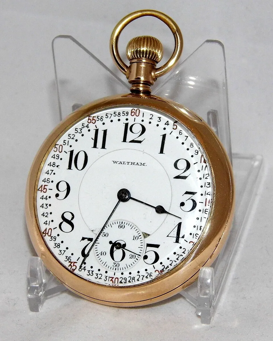 A gold Waltham pocket watch with a large white dial and separate seconds display