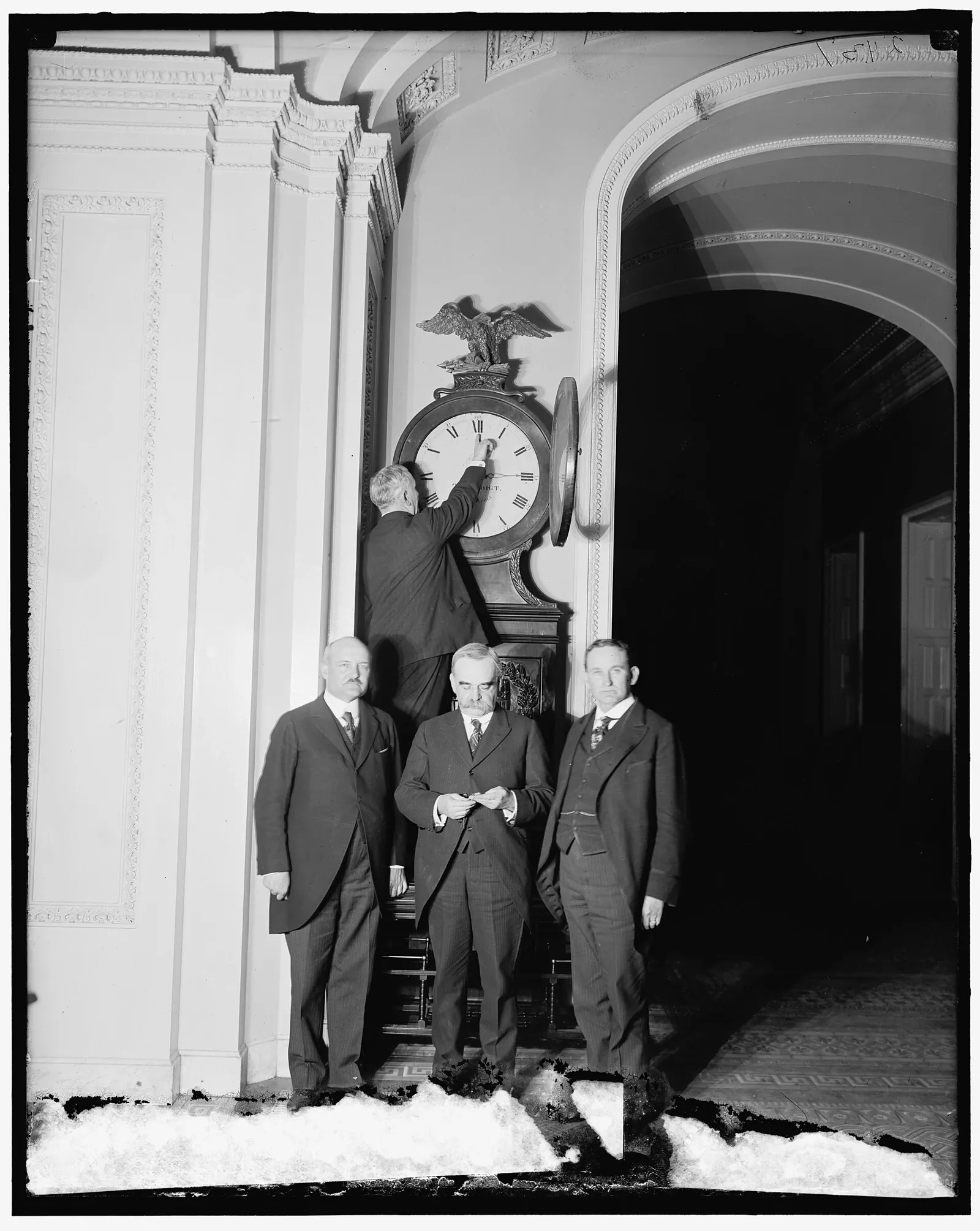 Charles Higgins reaching up to change the Senate Ohio Clock while three senators stand below