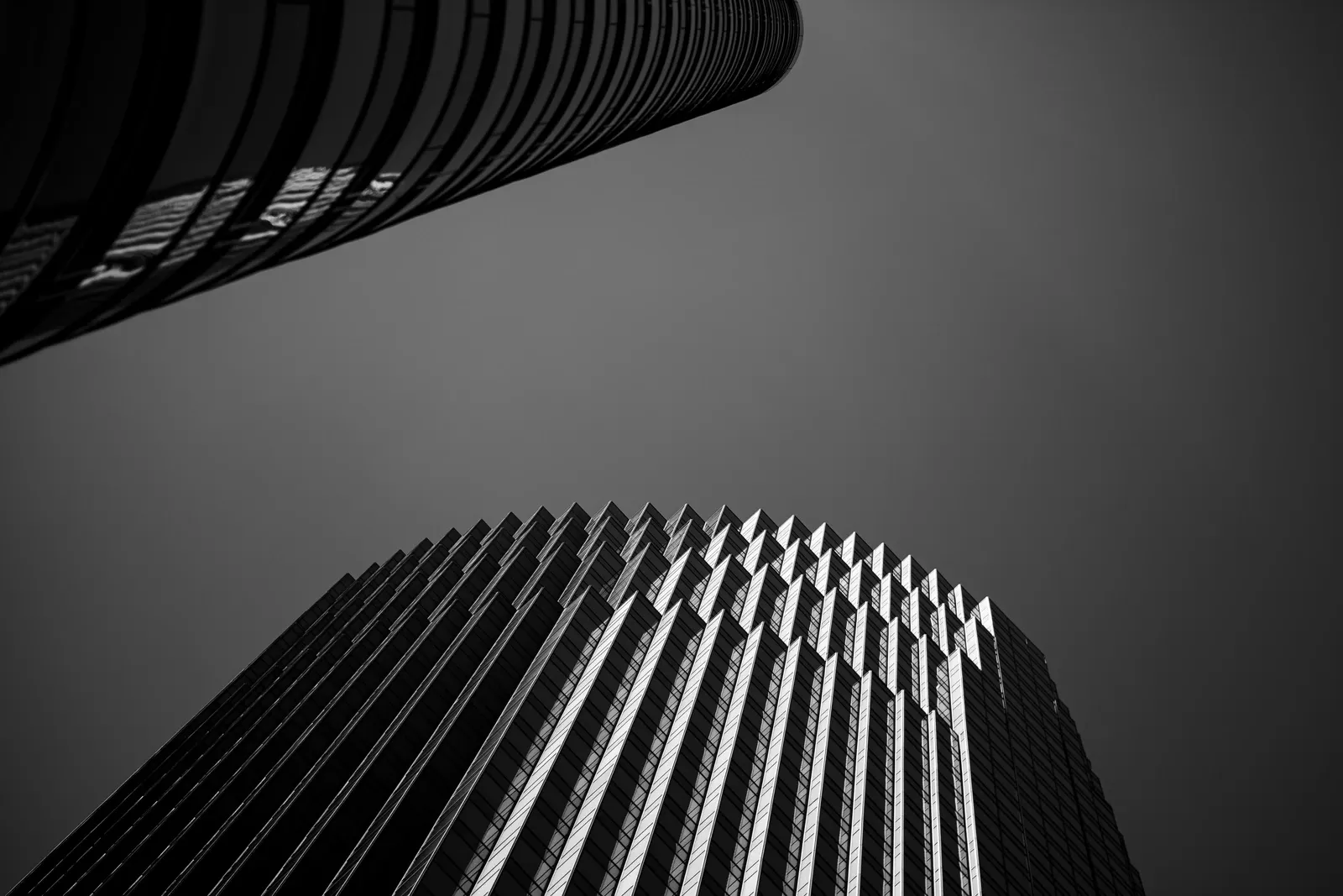 Two skyscrapers frame a restricted view of the sky in a black and white photograph.