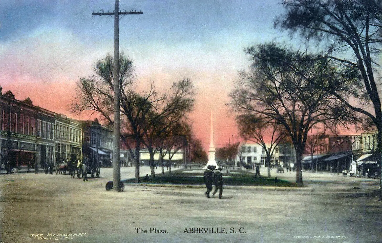A hand-colored postcard of Abbeville’s Court Square, with storefronts, trees, pedestrians and a central monument.