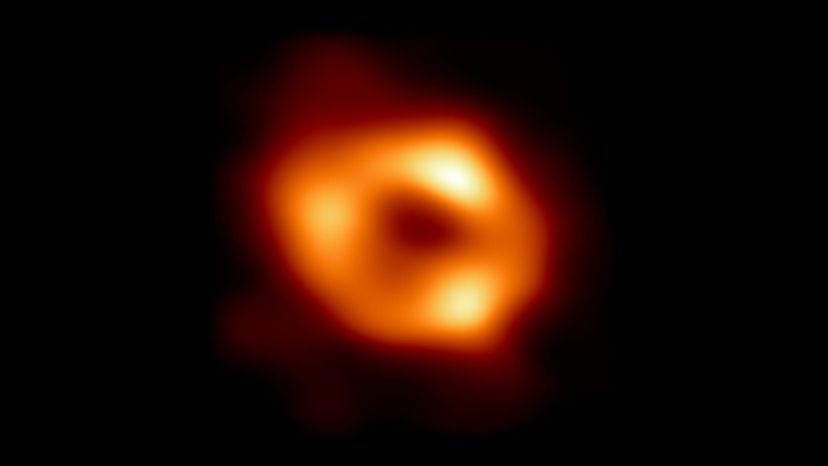 EHT image of Sagittarius A*: a bright orange ring around a dim central region.