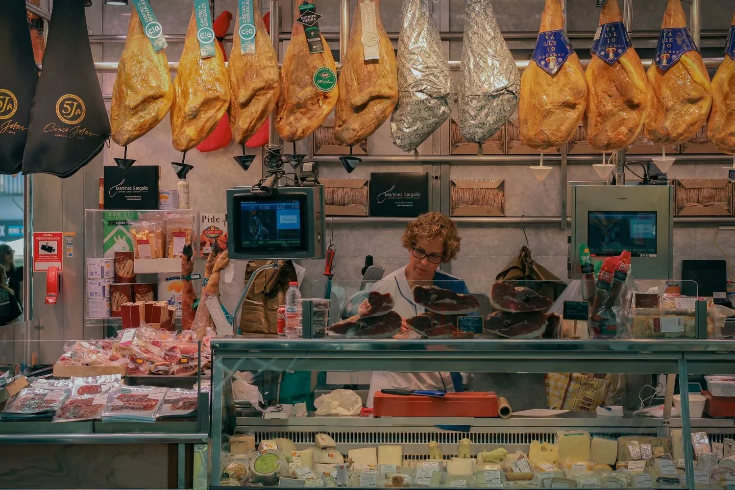 A bustling market stall in Valencia, Spain, showcasing jamón and various cheeses